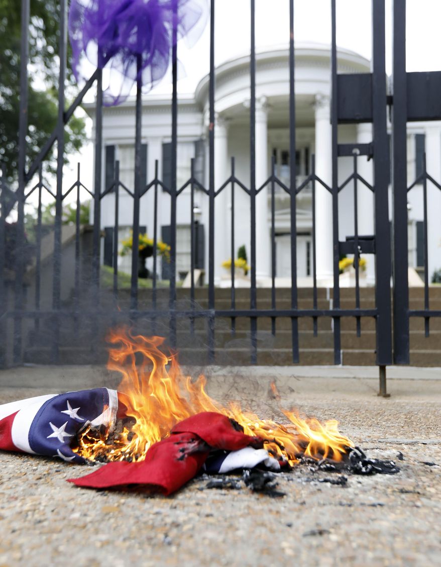 Remnants of a Mississippi state flag burn in front of the Governor's Mansion after members of the Mississippi Poor People's Campaign burned it and a Confederate battle flag in protest in Jackson, Miss., Monday, June 18, 2018. The campaign, held the last of its weekly protests in Jackson, joining a nationwide effort that called for lawmakers and statewide elected officials to address the need for union rights, living wages, fully funded anti-poverty programs and properly fund public education. (AP Photo/Rogelio V. Solis)