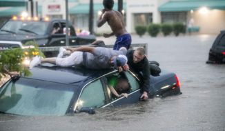 In this Monday, June 18, 2018, photo, Mark Pickett, left, and Ryan Craig, right, work to rescue Bruce Salley, who was trapped in his car by flood waters in a supermarket parking in Rockford, Ill. An evening thunderstorm brought heavy rains across the Rock River Valley causing vehicles to get stuck in flood waters and stranding motorists. (Arturo Fernandez/Rockford Register Star via AP)