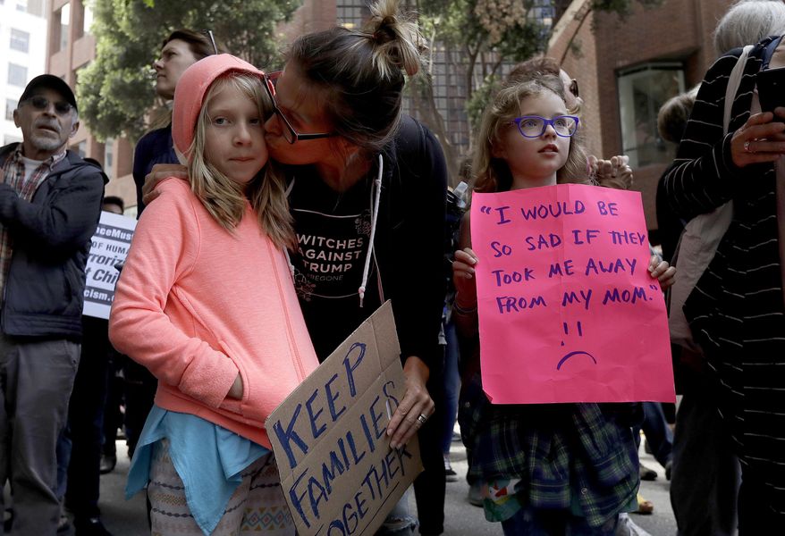 Kate Schatz, center, kisses her daughter Ivy Pontius, left, while protesting outside of the Immigration and Customs Enforcement (ICE) office with family friend Annea Berggren-Briggs, right, in San Francisco, Tuesday, June 19, 2018. (AP Photo/Jeff Chiu)