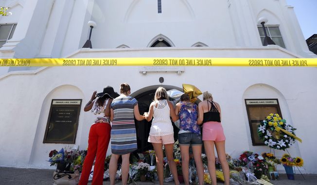 FILE - In this June 18, 2015, file photo, a group of women pray together at a makeshift memorial on the sidewalk in front of the Emanuel AME Church, in Charleston, S.C.  A judge dismissed a lawsuit, June 18, 2018, against the FBI for a faulty background check that allowed Dylann Roof to buy the gun he used to kill nine people in a racist attack at a South Carolina church.  U.S. District Judge Richard Gergel also blasted the federal government’s &amp;quot;abysmally poor policy choices&amp;quot; in running the database for firearm background checks.  (AP Photo/Stephen B. Morton, File)