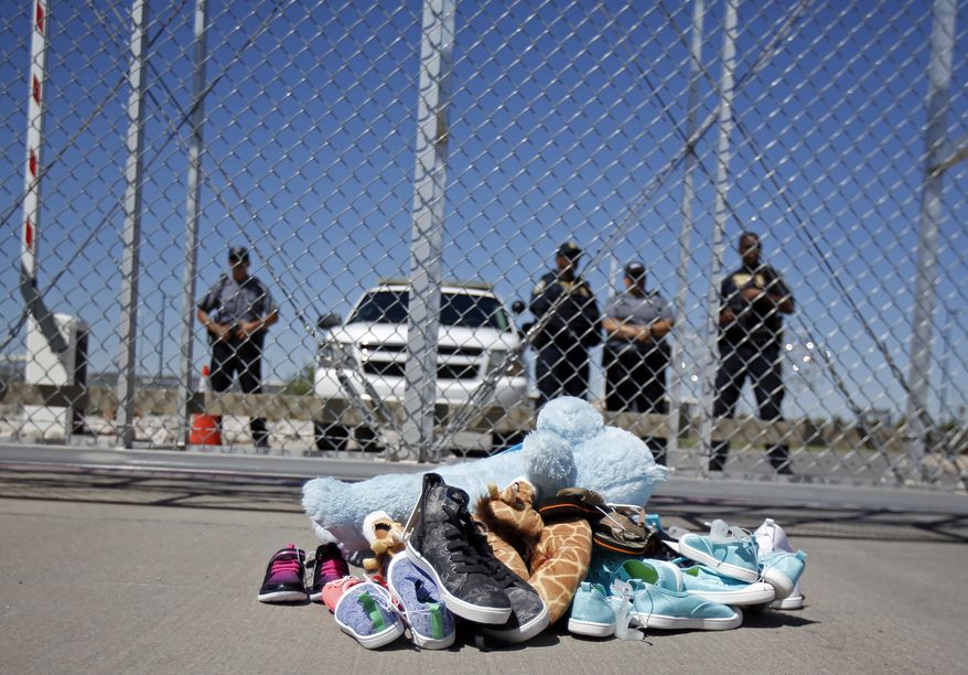 Shoes and a teddy bear, brought by a group of U.S. mayors, are piled up outside a holding facility for immigrant children in Tornillo, Texas, near the Mexican border, Thursday, June 21, 2018.  Mayors from more than a dozen U.S. cities including New York and Los Angeles gathered near the holding facility to call for the immediate reunification of immigrant children with their families.  (AP Photo/Andres Leighton)