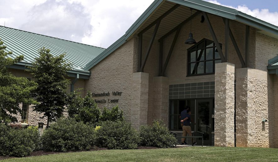 A person walks into the entrance of the Shenandoah Valley Juvenile Center on Wednesday, June 20, 2018 in Staunton, Va. Immigrant children as young as 14 housed at the juvenile detention center say they were beaten while handcuffed and locked up for long periods in solitary confinement, left nude and shivering in concrete cells. The abuse claims are detailed in federal court filings that include a half-dozen sworn statements from Latino teens jailed there for months or years. (AP Photo/Zachary Wajsgras)