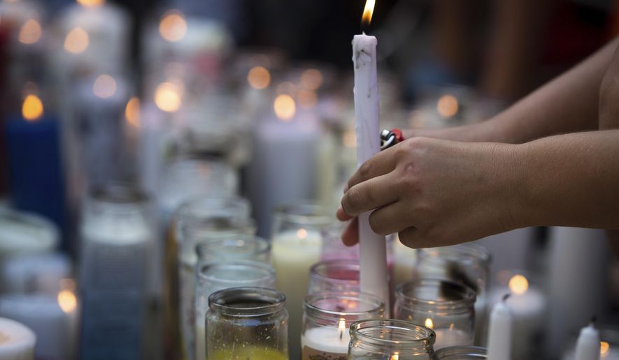 In this Tuesday, June 19, 2018 photo, fans and community members light candles as they gather at a vigil for rap singer XXXTentacion in Deerfield Beach, Fla., near the site where the troubled rapper-singer was killed the day before. The 20-year-old rising star, whose real name is Jahseh Dwayne Onfroy, was shot outside the motorcycle dealership on Monday, June 18, when two armed suspects approached him, authorities said. (Tuesday, June 19, 2018,/South Florida Sun-Sentinel via AP)