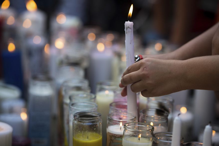 In this Tuesday, June 19, 2018 photo, fans and community members light candles as they gather at a vigil for rap singer XXXTentacion in Deerfield Beach, Fla., near the site where the troubled rapper-singer was killed the day before. The 20-year-old rising star, whose real name is Jahseh Dwayne Onfroy, was shot outside the motorcycle dealership on Monday, June 18, when two armed suspects approached him, authorities said. (Tuesday, June 19, 2018,/South Florida Sun-Sentinel via AP)