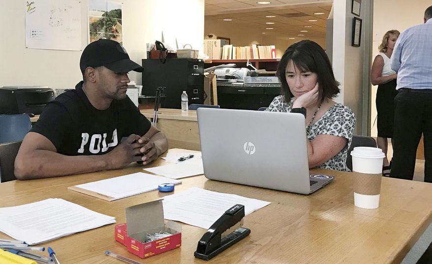 In this June 12, 2018, photo, Steven Martin, left, works with Chittenden County State's Attorney Sarah George in Burlington, Vt., on paperwork to remove a minor marijuana conviction from his record. Vermont is poised to legalize the recreational use of marijuana on July 1 and some jurisdictions are helping people remove previous marijuana convictions from their records. A number of other states and jurisdictions across the country have similar programs. (AP Photo/David Jordan)