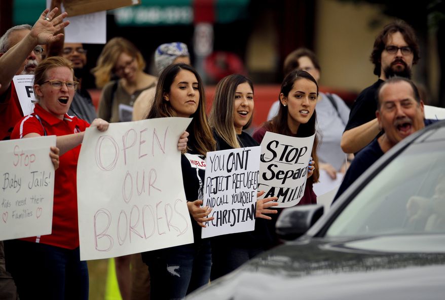 Protesters react to a passing motorist as they rally against U.S. immigration policies outside an office for Rep. Kevin Yoder Friday, June 22, 2018, in Overland Park, Kan. (AP Photo/Charlie Riedel)