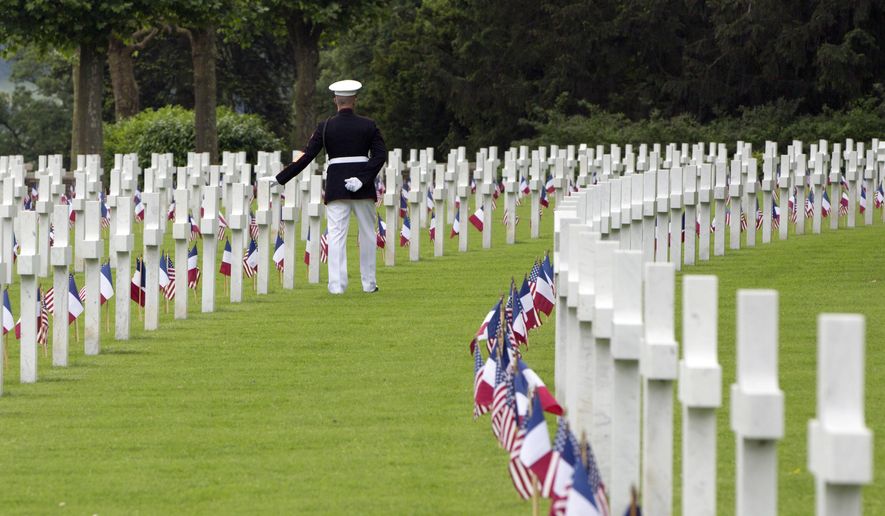 FILE - In this May 27, 2018, file photo, U.S. Marine Corps Sergeant Major Darrell Carver, based in North Carolina, touches a headstone at the Aisne-Marne American Cemetery in Belleau, France. France and Belgium are urging UNESCO to designate scores of their World War I memorials and cemeteries as World Heritage sites as the centennial remembrance of the 1914-1918 war nears its end. (AP Photo/Virginia Mayo, File)