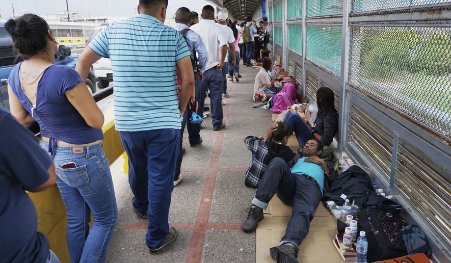 CORRECTS DATE TO JUNE 21, NOT 23 - In this Thursday, June 21, 2018 photo, migrant families rest from their travels to Matamoros, Mexico, along Gateway International Bridge which connects to Brownsville, Texas, as they seek asylum in the United States. (Miguel Roberts/The Brownsville Herald via AP)