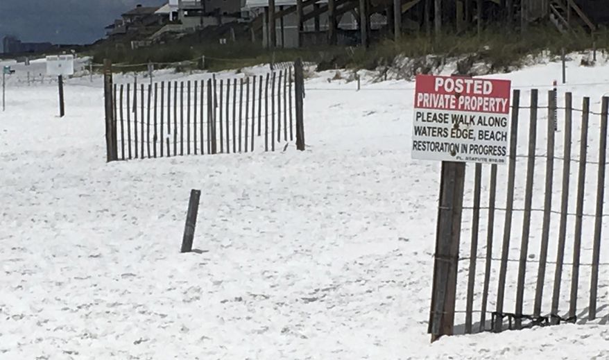 This May 15, 2018 photo shows a sign at the edge of a public beach marking where private beaches begin in Santa Rosa Beach, Fla. A new Florida law is set to reignite a fight over beach access in a Florida Panhandle county known for its pristine, sugar-white sand and rolling dunes, right in time for the July 4th holiday. Walton County Sheriff Michael Adkinson says the law that takes effect July 1 will void a local ordinance that allows public access to sand that's owned by beachfront property owners. If unwelcome beachgoers refuse to leave, they'll be arrested for trespassing. (AP Photo/Brendan Farrington)