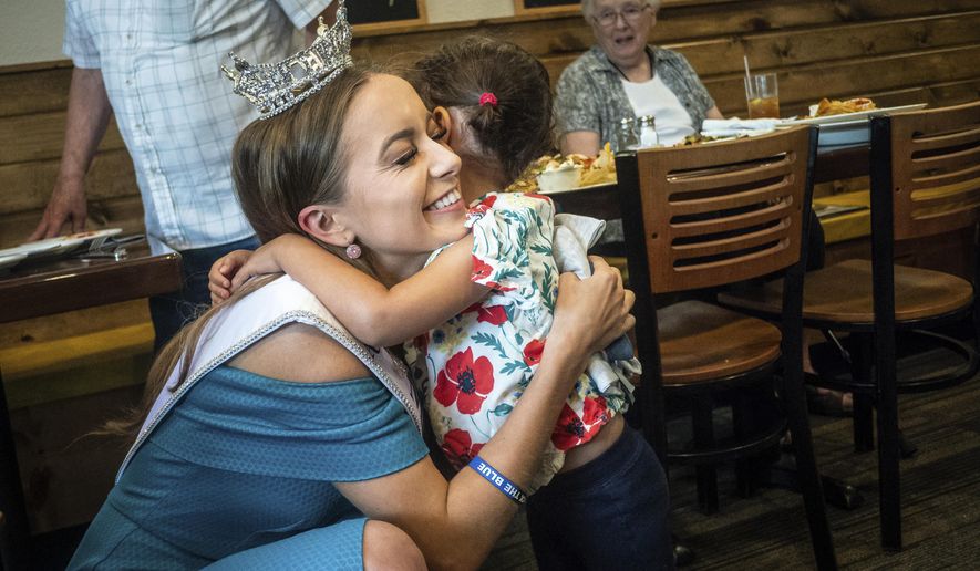 Michaelene Karlen, who was recently crowned Miss Minnesota 2018, gets a hug from 3-year-old Greta Schmitz, of Kasson, during an event congratulating Karlen Tuesday, June 19, 2018, at Daniel's Restaurant in her hometown of Kasson, Minn. "My heart is full," said Karlen of the crowd that came out to congratulate her. (Joe Ahlquist/The Rochester Post-Bulletin via AP)