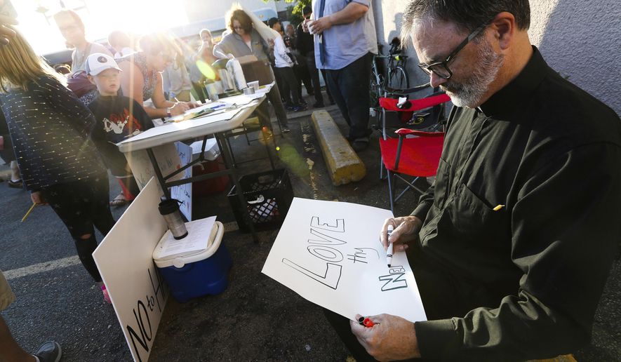 The Rev. Jay Rowland, of First Presbyterian Church in Rochester, Minn., creates a sign saying "Love thy Neighbor" before a sunrise solidarity vigil for the Rochester Muslim community, Sunday, June, 24, 2018, outside the Masjed Abubakr Al-Seddiq Islamic Center in downtown Rochester, Minn. The event was in response to bacon being found by the mosque's front door and in the parking lot Saturday morning, an act one group called “attempted religious desecration.” (Andrew Link/The Rochester Post-Bulletin via AP)