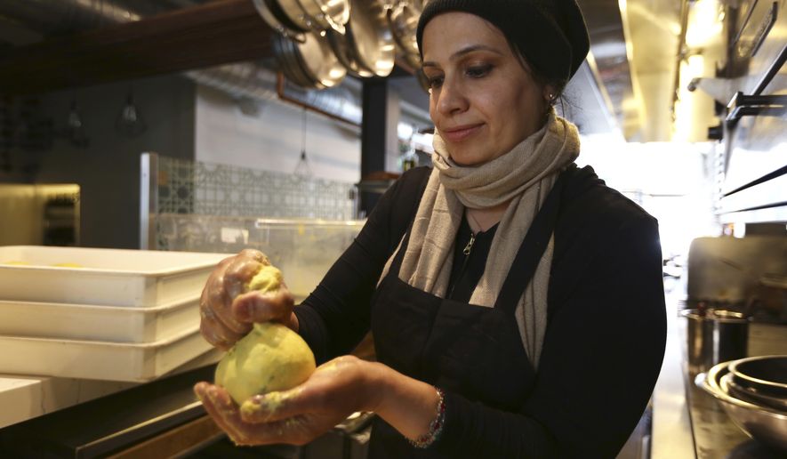 In this photo taken June 20, 2018, Muna Anaee, prepares a ball of khobz orouk, a flatbread she would eat frequently in her native Iraq, at the Tawla restaurant kitchen in San Francisco during the inaugural Refugee Food Festival. San Francisco restaurants are opening their kitchens for the first time to refugees who are showcasing their culinary skills and native cuisines while raising their profiles as aspiring chefs as part of a program to increase awareness about the plight of refugees worldwide. (AP Photo/Lorin Eleni Gill)