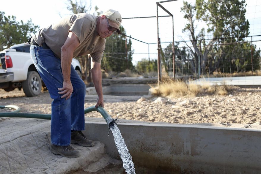 In this June 13, 2018 photo, Mike Anderson of the Arizona Elks Society fills a wildlife water tank off a forest road near Flagstaff, Ariz. Anderson volunteers with the Arizona Game and Fish Department, which is boosting efforts to ensure wildlife have water amid drought. (Ben Shanahan/Arizona Daily Sun via AP)