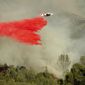 An air tanker drops retardant on a wildfire burning above the Spring Lakes community on Sunday, June 24, 2018, near Clearlake Oaks, Calif. Wind-driven wildfires destroyed buildings and threatened hundreds of others Sunday as they raced across dry brush in rural Northern California. (AP Photo/Noah Berger)