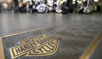 In this April 26, 2017, file photo, rows of motorcycles are behind a bronze plate with corporate information on the showroom floor at a Harley-Davidson dealership in Glenshaw, Pa. Harley-Davidson, facing rising costs from new tariffs, will begin shifting the production of motorcycles heading for Europe from the U.S. to factories overseas. (AP Photo/Keith Srakocic, File)