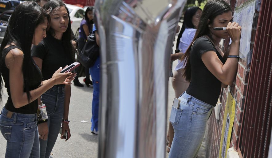 Yenisser Perez-Morillo, right, and many others sign posters at a memorial to Lesandro Guzman-Feliz near the site of the deadly attack in the Bronx borough of New York, Monday, June 25, 2018. Guerrero lives nearby and had gone to elementary school with the victim. Several suspects are in custody in New Jersey and awaiting extradition in connection with last week's killing of the 15-year-old boy in the Bronx that has sparked community outrage. Police said that Guzman-Feliz's death was gang related. The teen was attacked outside a bodega by a group of men and died after getting slashed in the neck with a machete. (AP Photo/Seth Wenig)