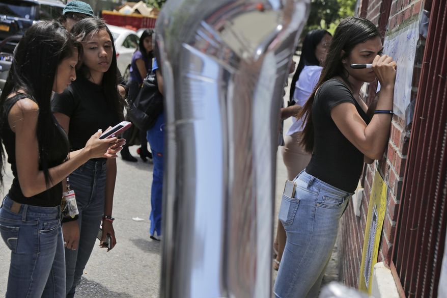 Yenisser Perez-Morillo, right, and many others sign posters at a memorial to Lesandro Guzman-Feliz near the site of the deadly attack in the Bronx borough of New York, Monday, June 25, 2018. Guerrero lives nearby and had gone to elementary school with the victim. Several suspects are in custody in New Jersey and awaiting extradition in connection with last week's killing of the 15-year-old boy in the Bronx that has sparked community outrage. Police said that Guzman-Feliz's death was gang related. The teen was attacked outside a bodega by a group of men and died after getting slashed in the neck with a machete. (AP Photo/Seth Wenig)