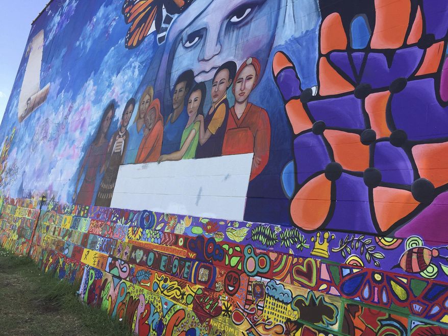 This Tuesday, June 26, 2018 photo shows where last-minute addition of an immigrant child clinging to her mother has been removed from a mural near the Brown v. Board of Education National Historic site in Topeka, Kan. The Kansas City Star reports that the image was painted over Monday on a 130-foot wide, 30-foot tall mural across from the former all-black school that tells the story of the U.S. Supreme Court ruling that ended segregated education. Artist bj McBride says she "couldn't help" adding the child Friday in response to the separation of parents and children at the U.S. border, but said later she thinks it was "distracting." (AP Photo/Mitchel Willetts)