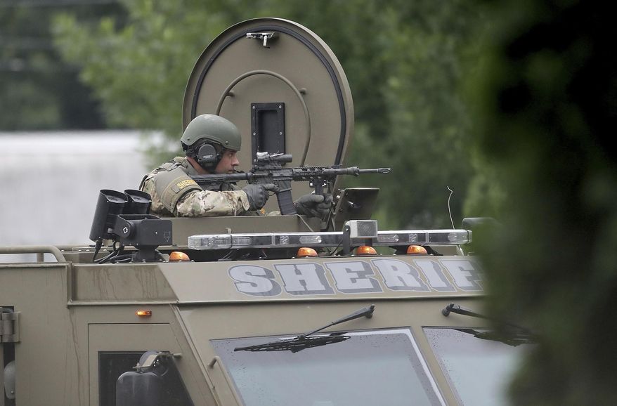 A sheriff's department SWAT team member keeps an eye toward the apartment where a man is barricaded Tuesday, June 26, 2018, in New Hope, Minn. A tense standoff in a New Hope, Minn., apartment between law enforcement and a man believed to be holding two children, and possibly a weapon, has stretched into Tuesday morning. (David Joles/Star Tribune via AP)