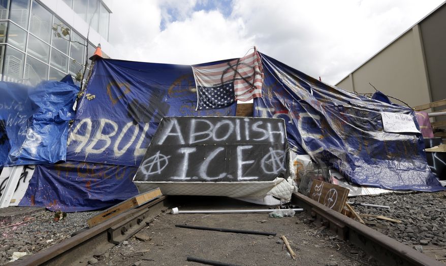 A barricade crosses railroad track at a protest camp on property outside the U.S. Immigration and Customs Enforcement office in Portland, Ore., Monday, June 25, 2018. Law enforcement officers began distributing notices to vacate to demonstrators late Monday morning. The round-the-clock demonstration outside the Portland headquarters began June 17, 2018, and increased in size early last week, prompting officials to close the facility. (AP Photo/Don Ryan)