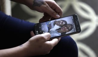 During an interview with The Associated Press Wednesday, June 27, 2018, in Evanston, Illinois,  Lidia Karine Souza, who is seeking asylum from Brazil, flips through her phone at photographs of her and her son Diogo as she talks about the ordeal she has lived in searching for and finally seeing her son for the first time on Tuesday. It took Souza weeks to find Diogo after he was taken from her at the Texas border in late May and sent by the government to a Chicago shelter.   (AP Photo/Charles Rex Arbogast)