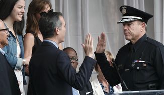 Los Angeles Mayor Eric Garcetti, left, swears in longtime Police Department veteran Michel Moore as Los Angeles&#39;s new police chief at the police academy on Thursday, June 28, 2018. Moore replaces Charlie Beck, who retired Wednesday, June 27, after more than 40 years with the LAPD.   (AP Photo/Richard Vogel)