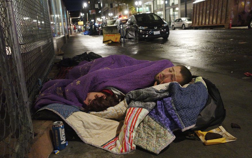 FILE--In this Sept. 18, 2017, file photo, Taz Harrington, right, sleeps with his girlfriend, Melissa Ann Whitehead, on a street in downtown Portland, Ore. A recent analysis found that one in every two arrests made by the Portland Police Bureau last year was of a homeless person. (AP Photo/Ted S. Warren, file)
