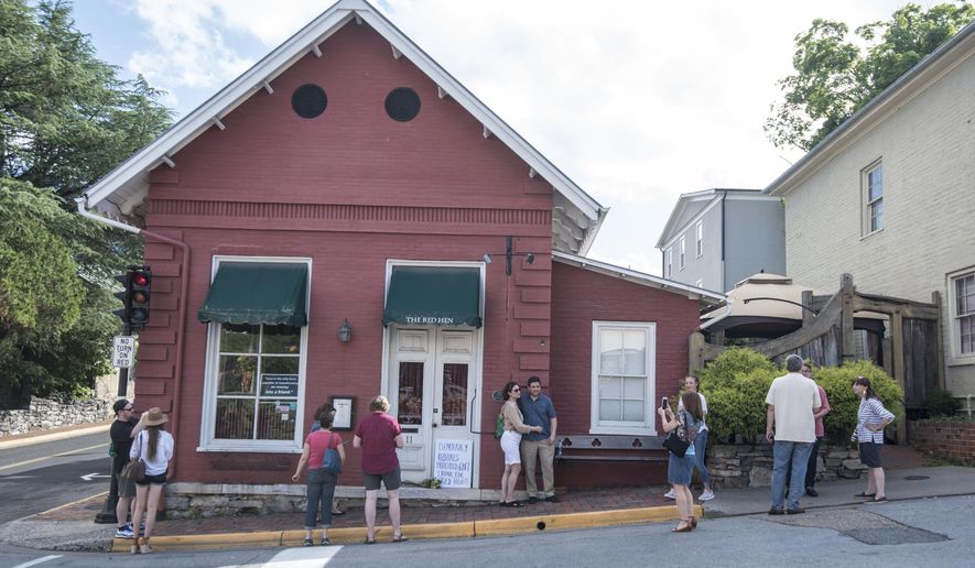 FILE- In this June 23, 2018, file photo, passersby gather to take photos in front of the Red Hen Restaurant in Lexington, Va. The restaurant has become internationally famous since ousting Sarah Huckabee Sanders over the weekend. (AP Photo/Daniel Lin, File)