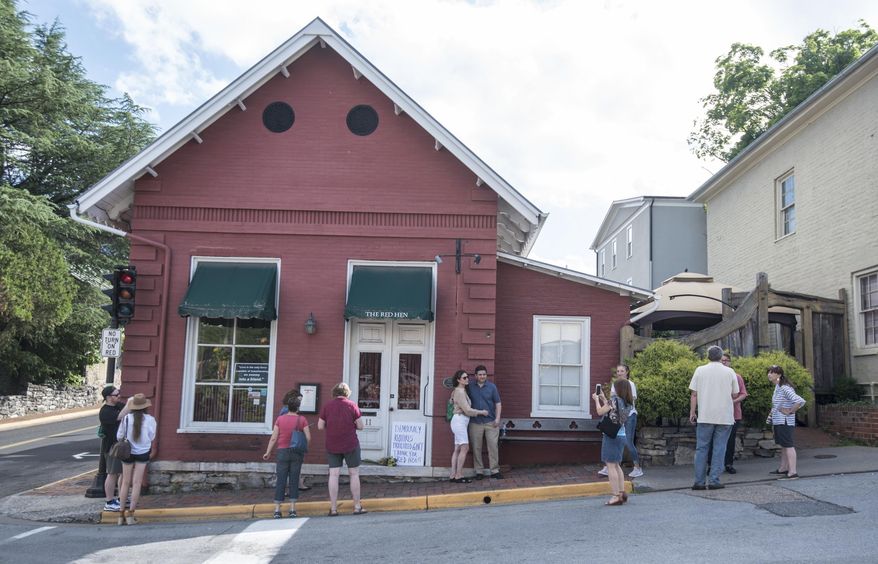 FILE- In this June 23, 2018, file photo, passersby gather to take photos in front of the Red Hen Restaurant in Lexington, Va. The restaurant has become internationally famous since ousting Sarah Huckabee Sanders over the weekend. (AP Photo/Daniel Lin, File)