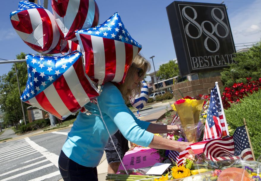 Kathaleen Novick place flowers at makeshift memorial in the scene were five journalist were shot at their newspaper office in Annapolis, Md., Friday, June 29, 2018. A man armed with smoke grenades and a shotgun attacked journalists in the building Thursday, killing several people before police quickly stormed the building and arrested him, police and witnesses said. (AP Photo/Jose Luis Magana)