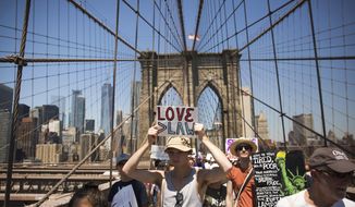 Activists carry signs across the Brooklyn Bridge during a rally to protest the Trump administration&#39;s immigration policies Saturday, June 30, 2018, in New York, New York. (AP Photo/Kevin Hagen)