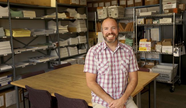 In this June 21, 2018 photo, Jeremy Johnson, State of Alaska Division of Elections Region III Elections Supervisor, poses in the supply room in the Division of Elections office in downtown Fairbanks, Alaska. Johnson went to college to get a degree in biology, but a perfectly timed internship in the Capitol in Juneau diverted him toward local and state politics. (Eric Engman/Fairbanks Daily News-Miner via AP)