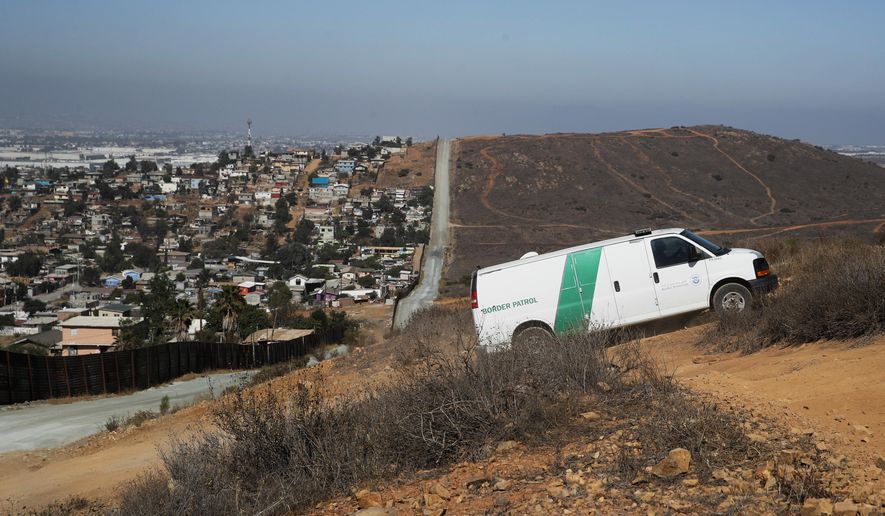 A U.S. Border Patrol van drives up the hill to pick up migrants apprehended trying to cross the U.S.-Mexico border illegally as the Mexican land looks on the left side of the border wall along a road Thursday, June 28, 2018, in San Diego. (AP Photo/Jae C. Hong, File)