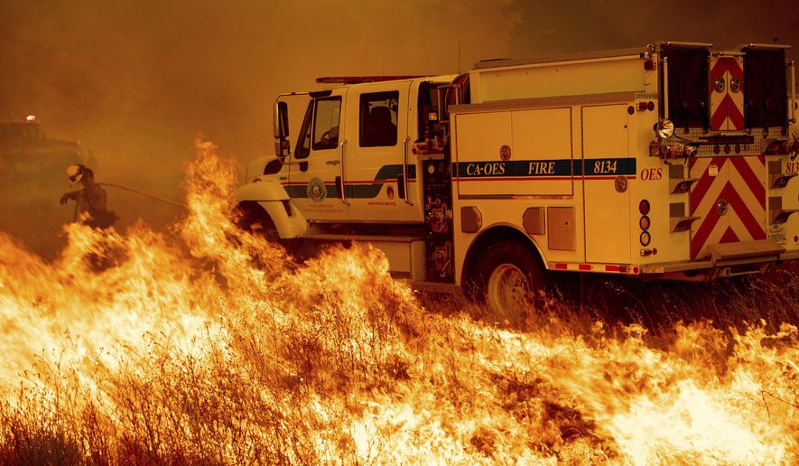 A firefighter scrambles to stop the Pawnee fire as it spots across Highway 20 near Clearlake Oaks, Calif., on Sunday, July 1, 2018. (AP Photo/Noah Berger)