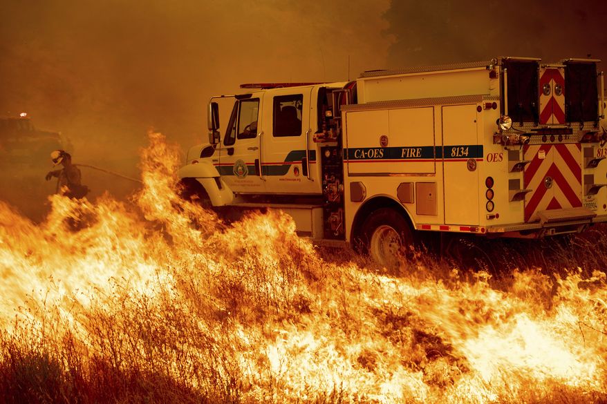 A firefighter scrambles to stop the Pawnee fire as it spots across Highway 20 near Clearlake Oaks, Calif., on Sunday, July 1, 2018. (AP Photo/Noah Berger)