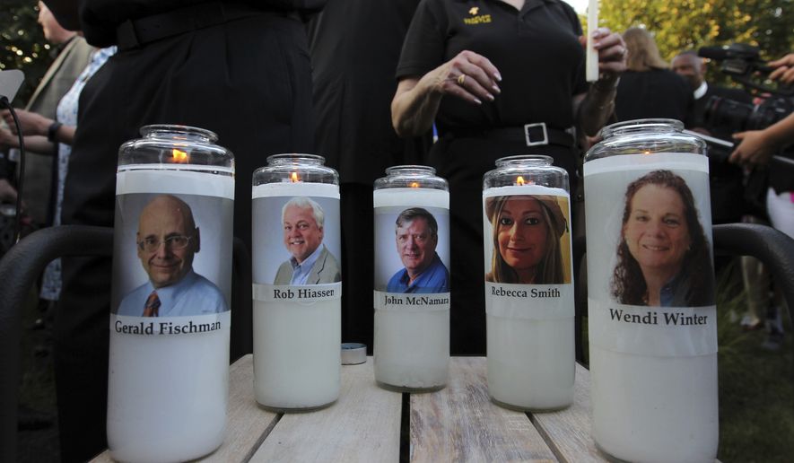 Photos of five journalists adorn candles during a vigil across the street from where they were slain in their newsroom in Annapolis, Md., Friday, June 29, 2018. Prosecutors say Jarrod W. Ramos opened fire Thursday in the Capital Gazette newsroom. (AP Photo/Jose Luis Magana)