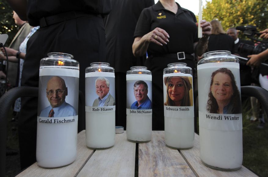 Photos of five journalists adorn candles during a vigil across the street from where they were slain in their newsroom in Annapolis, Md., Friday, June 29, 2018. Prosecutors say Jarrod W. Ramos opened fire Thursday in the Capital Gazette newsroom. (AP Photo/Jose Luis Magana)