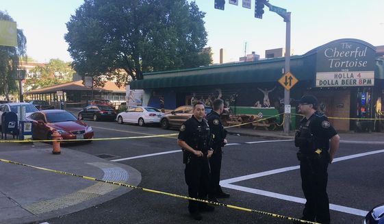 FILE - In this June 29, 2018, file photo, police officers stand at the scene of an earlier shooting outside The Cheerful Tortoise bar in Portland, Ore. A black man who was fatally shot by Portland State University campus police during a fight outside the bar had a permit to carry a concealed handgun. (Shane Dixon/The Oregonian via AP, File)