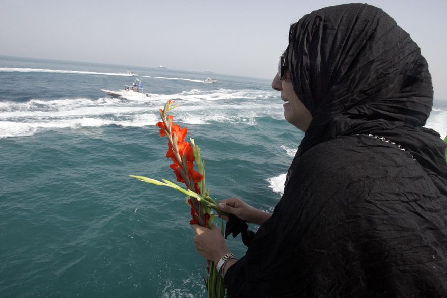 FILE - In this Monday, July 2, 2012 file photo, Najmeh Arshad, an Iranian woman whose father was killed when a U.S. warship shot down an Iranian airliner 24 years ago, scatters flowers into the Persian Gulf during a ceremony remembering the 290 passengers at the spot where the airliner was downed. In the waters of the Persian Gulf just off Iran, mourners tossed flowers from a helicopter and a ferry Tuesday to mark the 30th anniversary of the U.S. Navy shooting down of an Iranian commercial airline, killing 290 people. (AP Photo/Vahid Salemi, File)