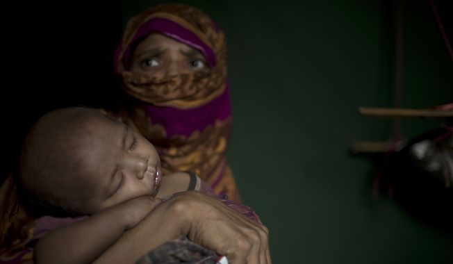 In this Monday, June 25, 2018, photo, &quot;S&quot; holds her baby boy as she sits in her shelter in Kutupalong refugee camp in Bangladesh. &quot;S,&quot; a widow, was so worried about her neighbors discovering her pregnancy that she suffered silently through labor in her shelter, stuffing a scarf in her mouth to swallow her screams. (AP Photo/Wong Maye-E)