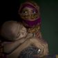 In this Monday, June 25, 2018, photo, &quot;S&quot; holds her baby boy as she sits in her shelter in Kutupalong refugee camp in Bangladesh. &quot;S,&quot; a widow, was so worried about her neighbors discovering her pregnancy that she suffered silently through labor in her shelter, stuffing a scarf in her mouth to swallow her screams. (AP Photo/Wong Maye-E)