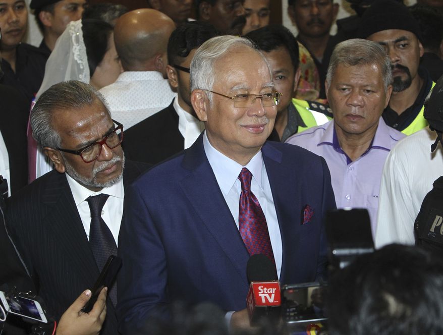 Former Malaysian Prime Minister Najib Razak, center, speaks to reporters as he leaves the courthouse in Kuala Lumpur, Malaysia, Wednesday, July 4, 2018. Najib was charged Wednesday with criminal breach of trust and corruption, two months after a multibillion-dollar graft scandal at a state investment fund led to his shock election defeat. (AP Photo/YC Hiam)