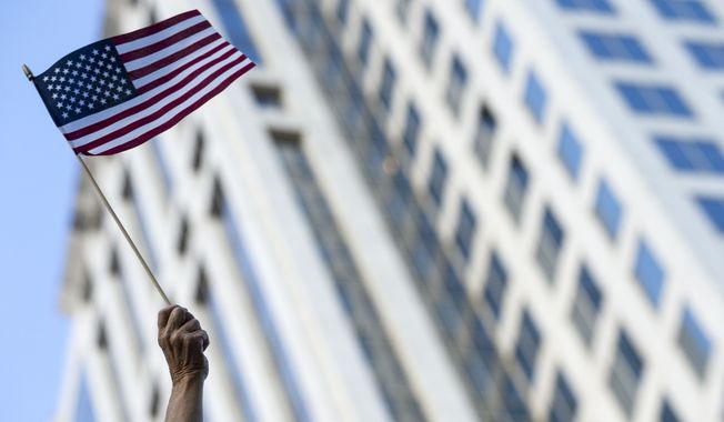 A woman waves an American flag during the 2018 AJC Peachtree Road Race in Atlanta, Wednesday, July 4, 2018. (Alyssa Pointer/Atlanta Journal-Constitution via AP)