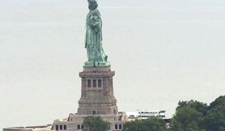 In this image taken from video, people climb on the pedestal of the Statue of Liberty in New York Harbor Wednesday, July 4, 2018. A person scaled the statue’s base and forced its evacuation shortly after several other people were arrested for hanging a banner from the pedestal that called for abolishing the Immigration and Customs Enforcement agency. (AP Photo)