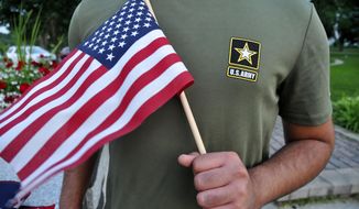 In this Tuesday, July 3, 2018, photo, a Pakistani recruit, 22, who was recently discharged from the U.S. Army, holds an American flag as he poses for a picture. The man asked his name and location to be undisclosed for safety reasons. The AP interviewed three recruits from Brazil, Pakistan and Iran, all of whom said they were devastated by their unexpected discharges. (AP Photo/Mike Knaak)
