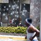 People move past the Best Western hotel during a protest over the cost of fuel in Port-au-Prince, Haiti, Saturday, July 7, 2018. The Haitian government suspended a fuel price hike Saturday hours after demonstrators attacked a Best Western Premiere hotel in one of the wealthiest neighborhoods of the capital. (AP Photo/Dieu Nalio Chery)
