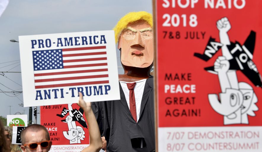 A protester marches next to giant puppet of U.S. President Donald Trump, right, as he holds a sign that reads &quot;Pro-America, Anti-Trump&quot; during a demonstration in Brussels, Saturday, July 7, 2018. (AP Photo/Geert Vanden Wijngaert)