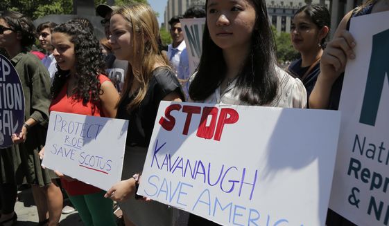 People hold signs at a rally opposing supreme court nominee Brett Kavanaugh in New York, Tuesday, July 10, 2018. (AP Photo/Seth Wenig)