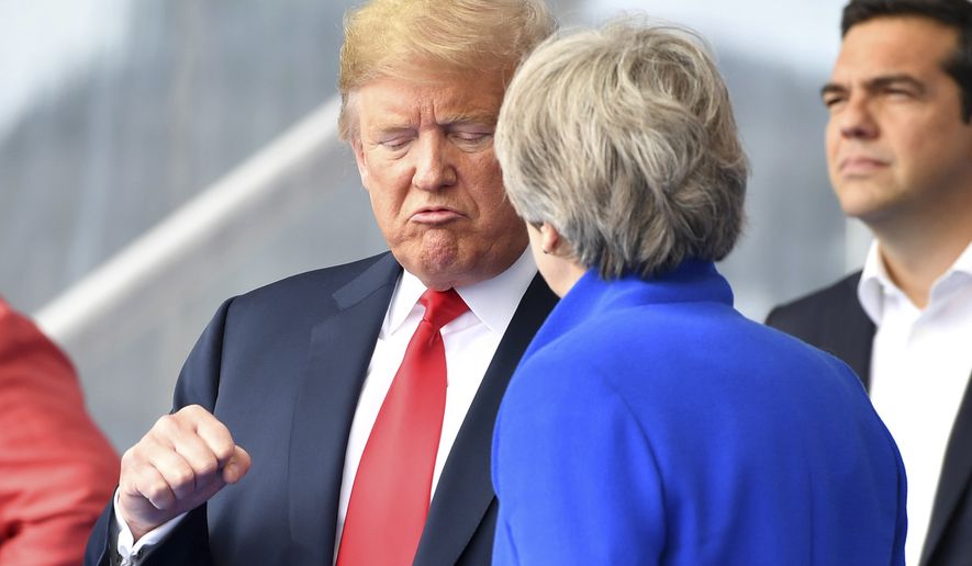 U.S. President Donald Trump, left, clenches a fist when talking to British Prime Minister Theresa May during a summit of heads of state and government at NATO headquarters in Brussels on Wednesday, July 11, 2018. NATO leaders gather in Brussels for a two-day summit to discuss Russia, Iraq and their mission in Afghanistan. (AP Photo/Geert Vanden Wijngaert)