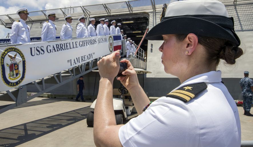 FILE - In this June 10, 2017 file photo, U.S. Navy Lt. Miranda Williams photographs sailors as they board the USS Gabrielle Giffords during a commissioning ceremony in Galveston, Texas. The Navy said Tuesday, July 10, 2018, it will let women sailors sport ponytails and other longer hairstyles, reversing a policy that long forbade females from letting their hair down. (Stuart Villanueva/The Galveston County Daily News via AP, File)